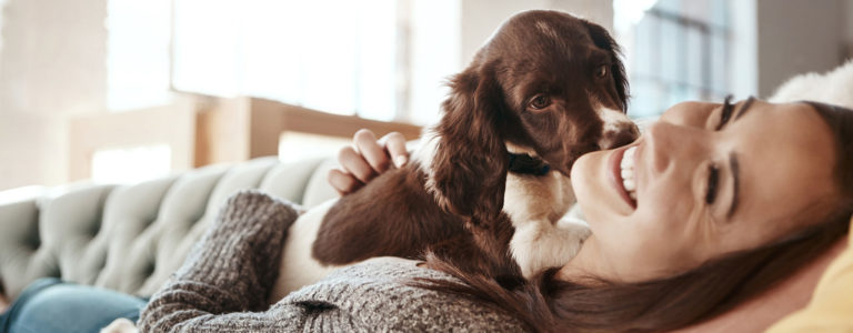 woman laying on couch with puppy