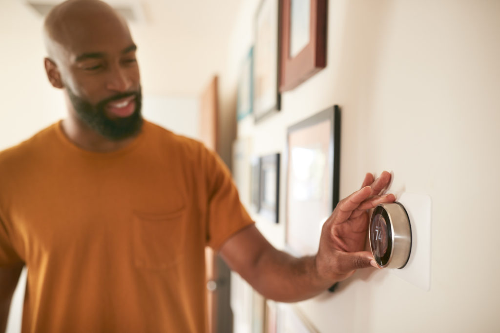 A man adjusts a smart thermostat.