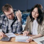 Two people sitting next to each other, working on their late rent paperwork.