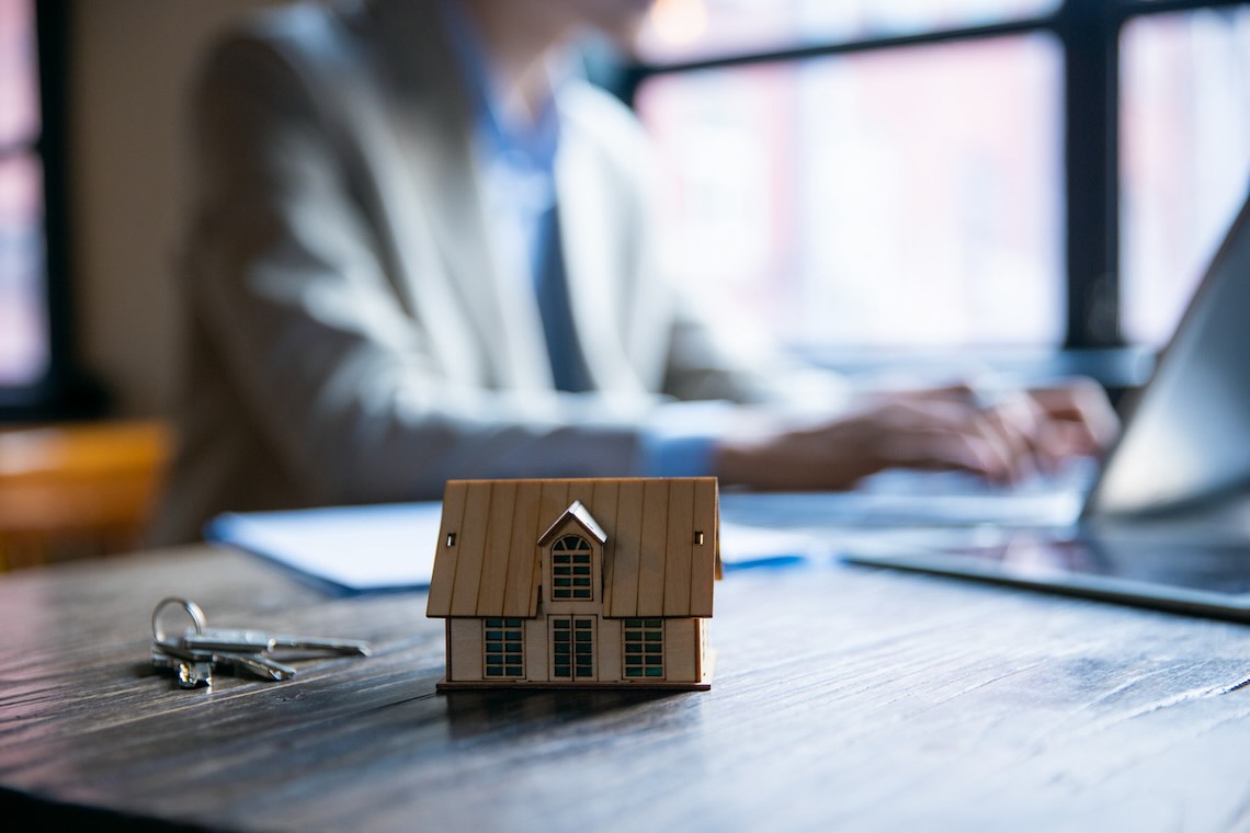 landlord working at laptop with model house in the foreground